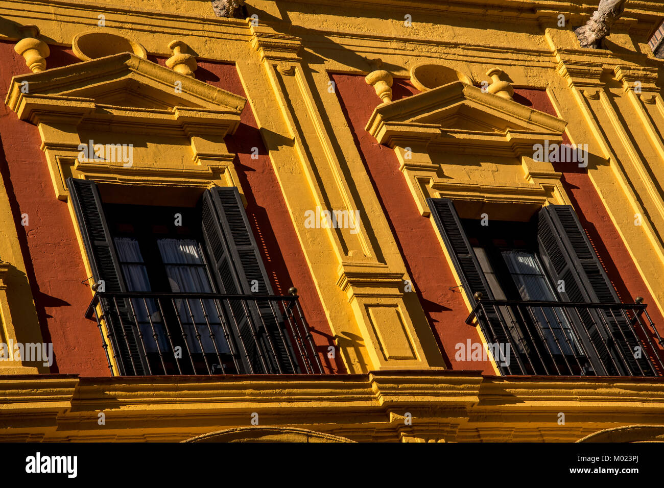 MALAGA, ANDALUSIA / SPAIN - OCTOBER 05 2017: BLACK WINDOW FRAMES ON YELLOW WALL Stock Photo