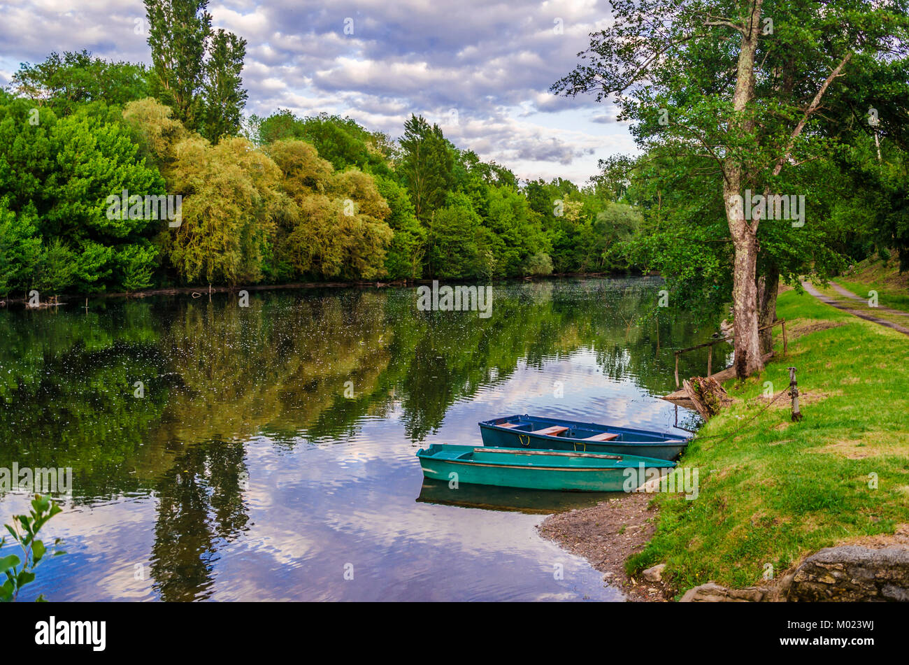 Valley of the river Dordogne two boats moored in the calm waters of the Dordogne in its passage through the village of Carennac France Stock Photo