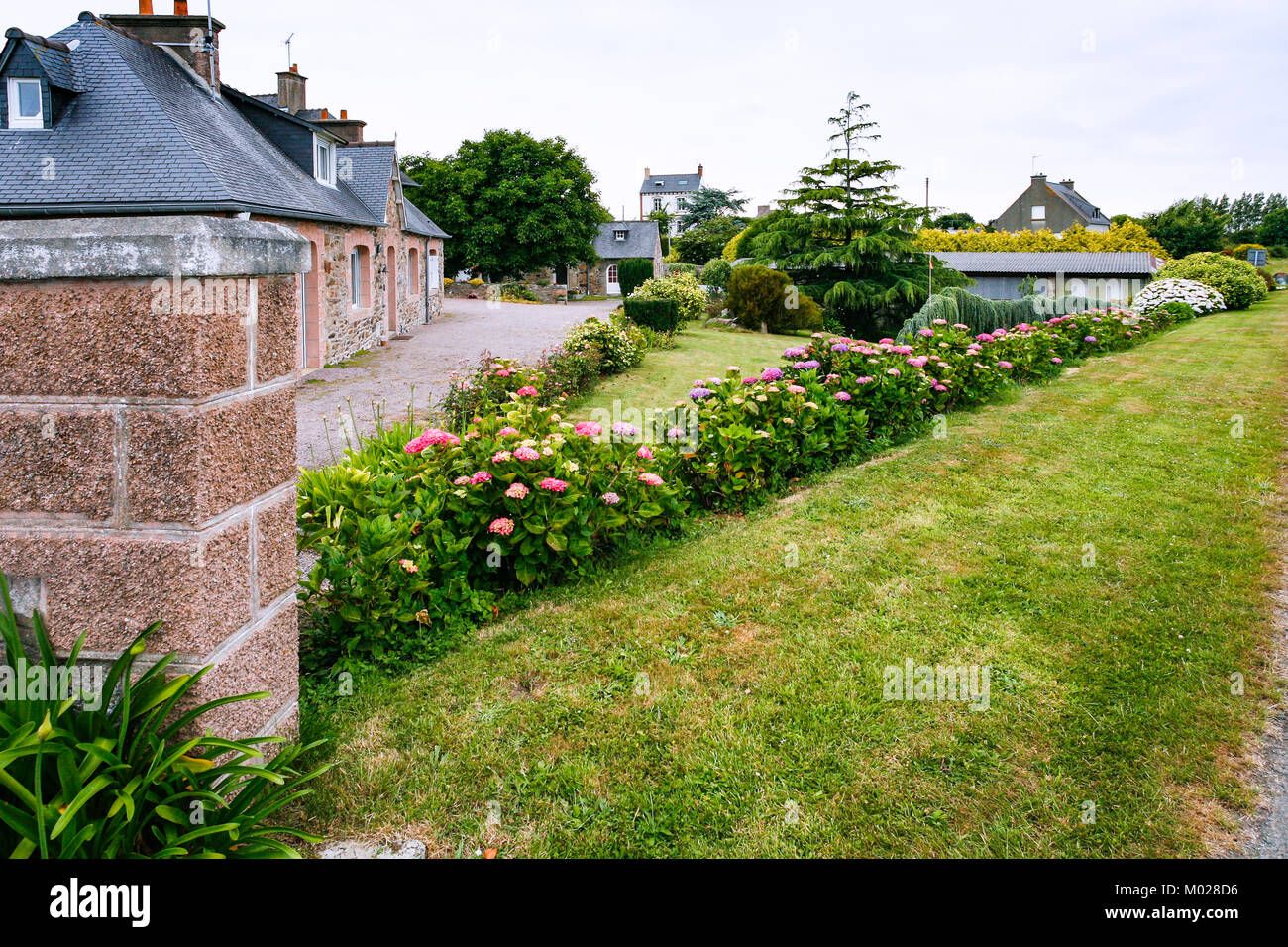 travel to France - street with flowerbed in Ploubazlanec commune of Paimpol region in Cotes-d'Armor department of Brittany in summer eveining Stock Photo