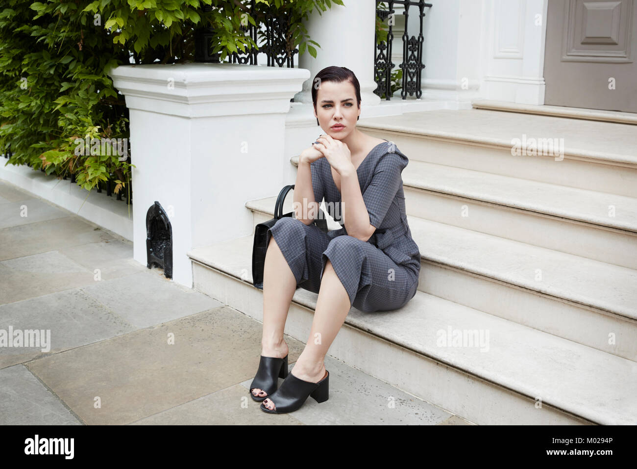 Chic woman waiting on doorstep in London street, horizontal Stock Photo