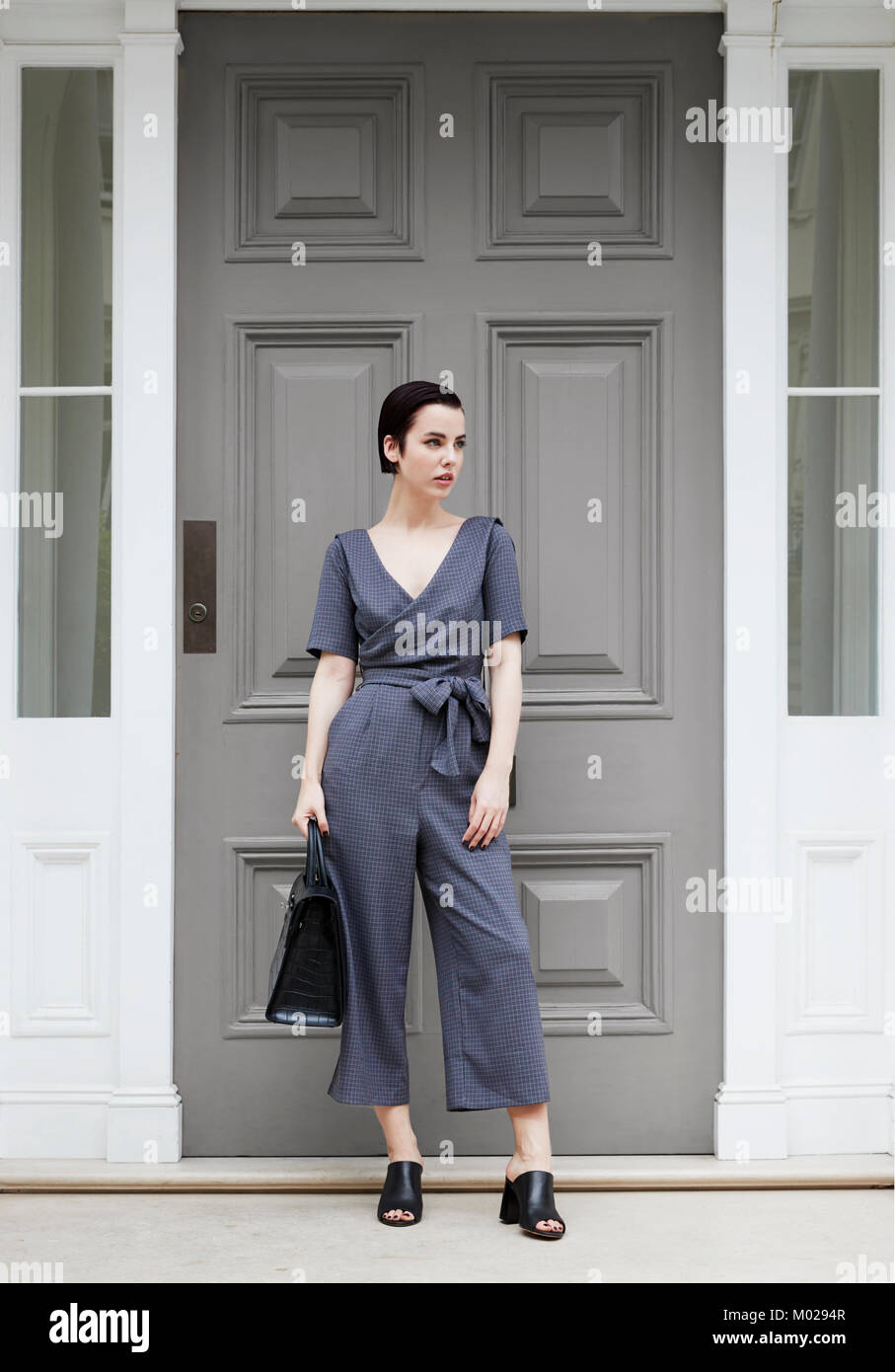 Chic woman in jumpsuit standing outside smart London house Stock Photo