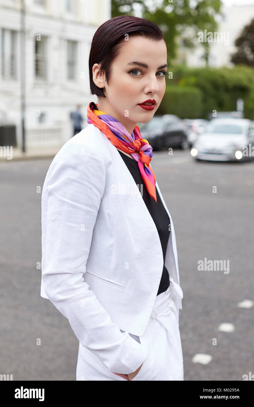 Woman standing in street wearing short white linen jacket Stock Photo