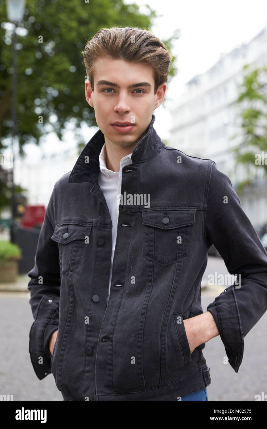 Young man in black denim jacket with hands in pockets Stock Photo