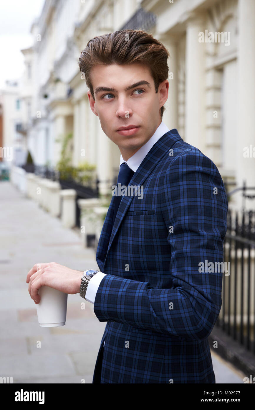 Young man in blue check suit in street with coffee, close up Stock Photo