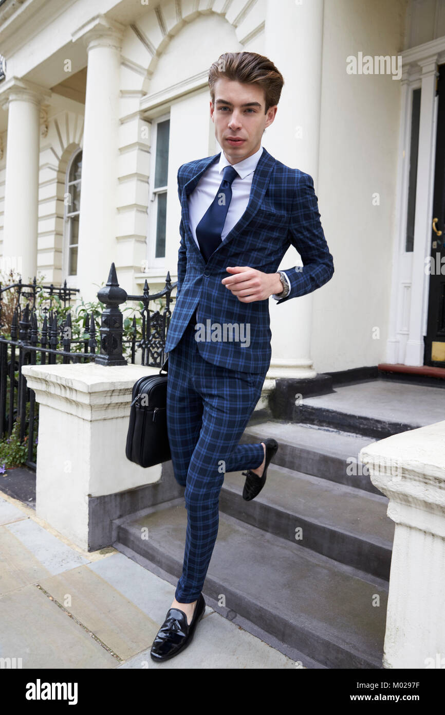 Young man in checked suit leaving smart London house Stock Photo