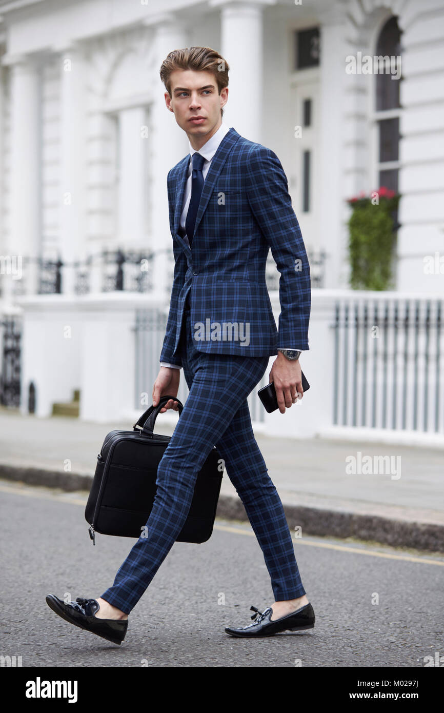 Young man in blue checked suit walking across the road Stock Photo