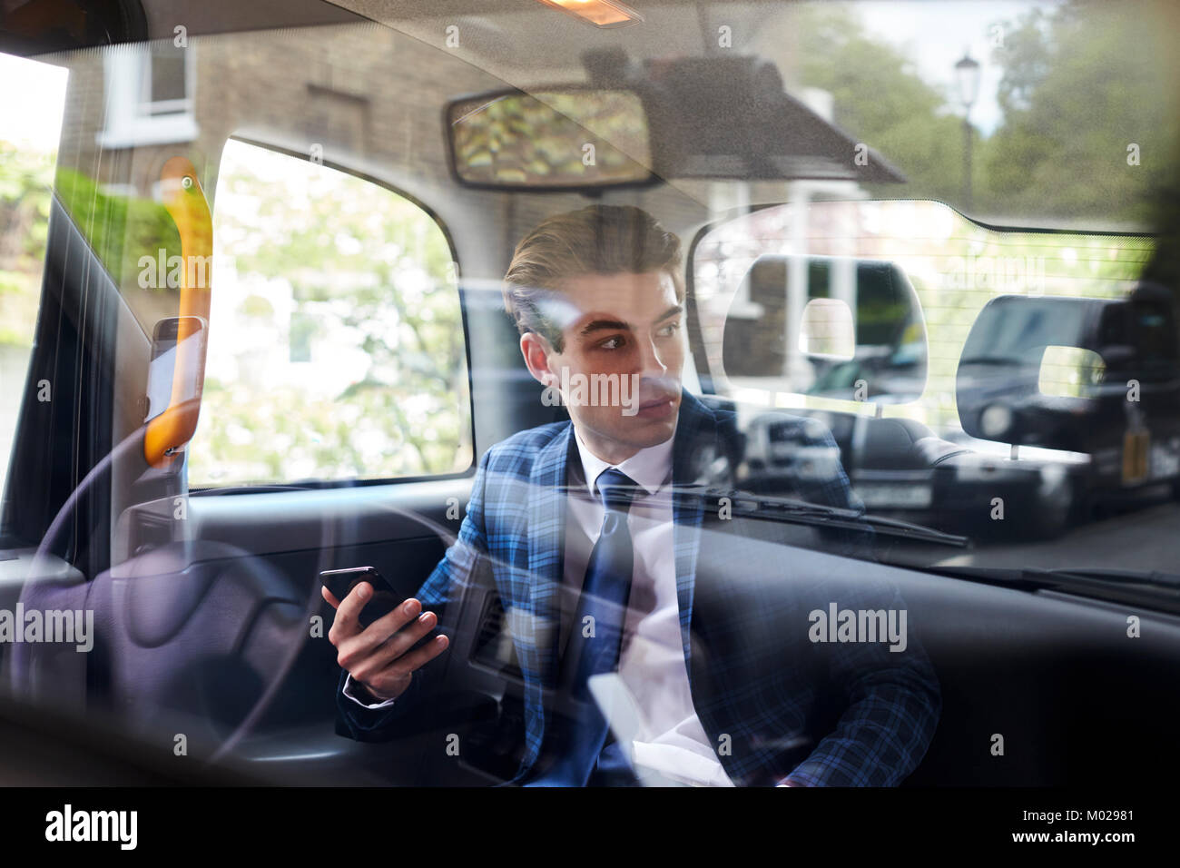 Young businessman in back of London taxi, seen through glass Stock Photo