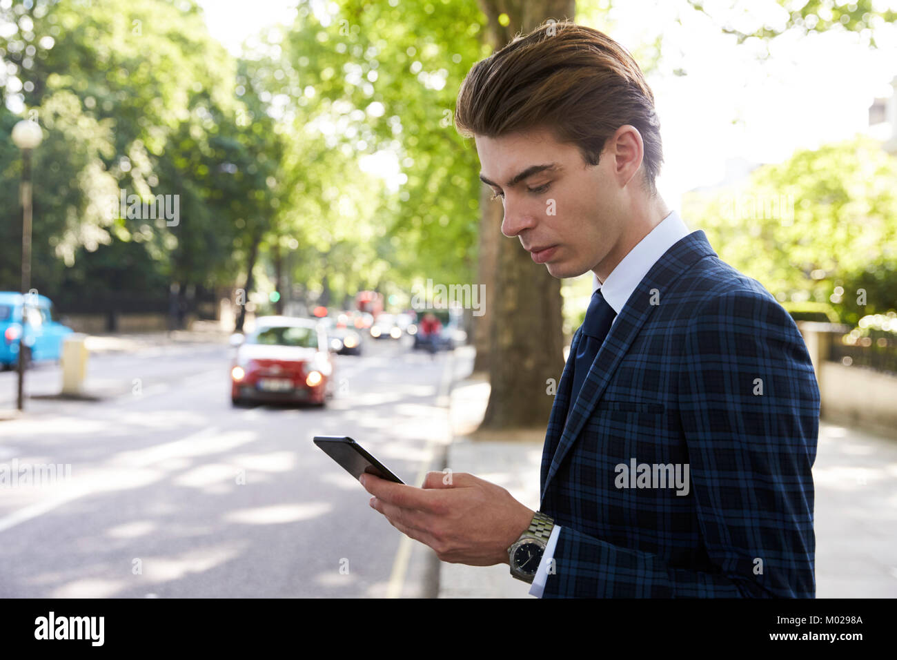 Young businessman standing in the street using smartphone Stock Photo