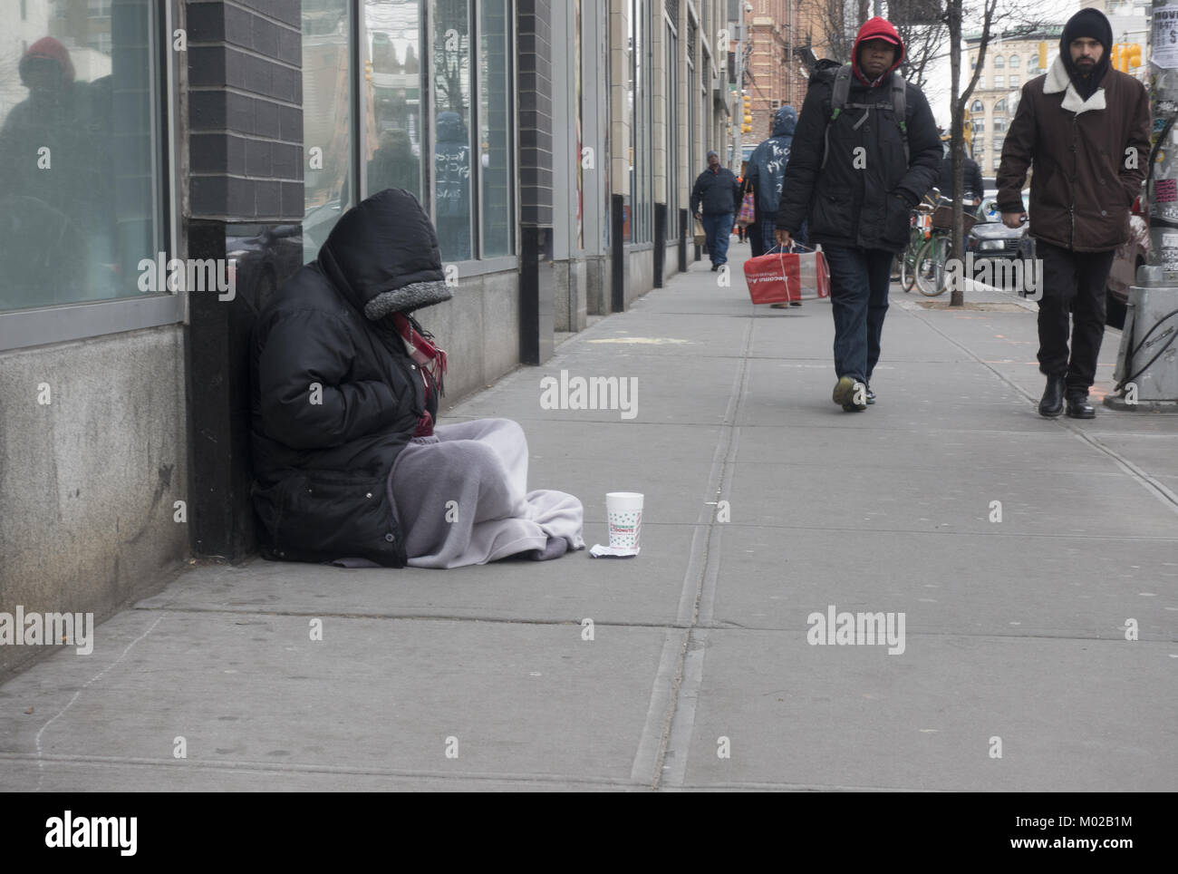Homeless person sitting on the sidewalk asking for money in midtown Manhattan. Stock Photo