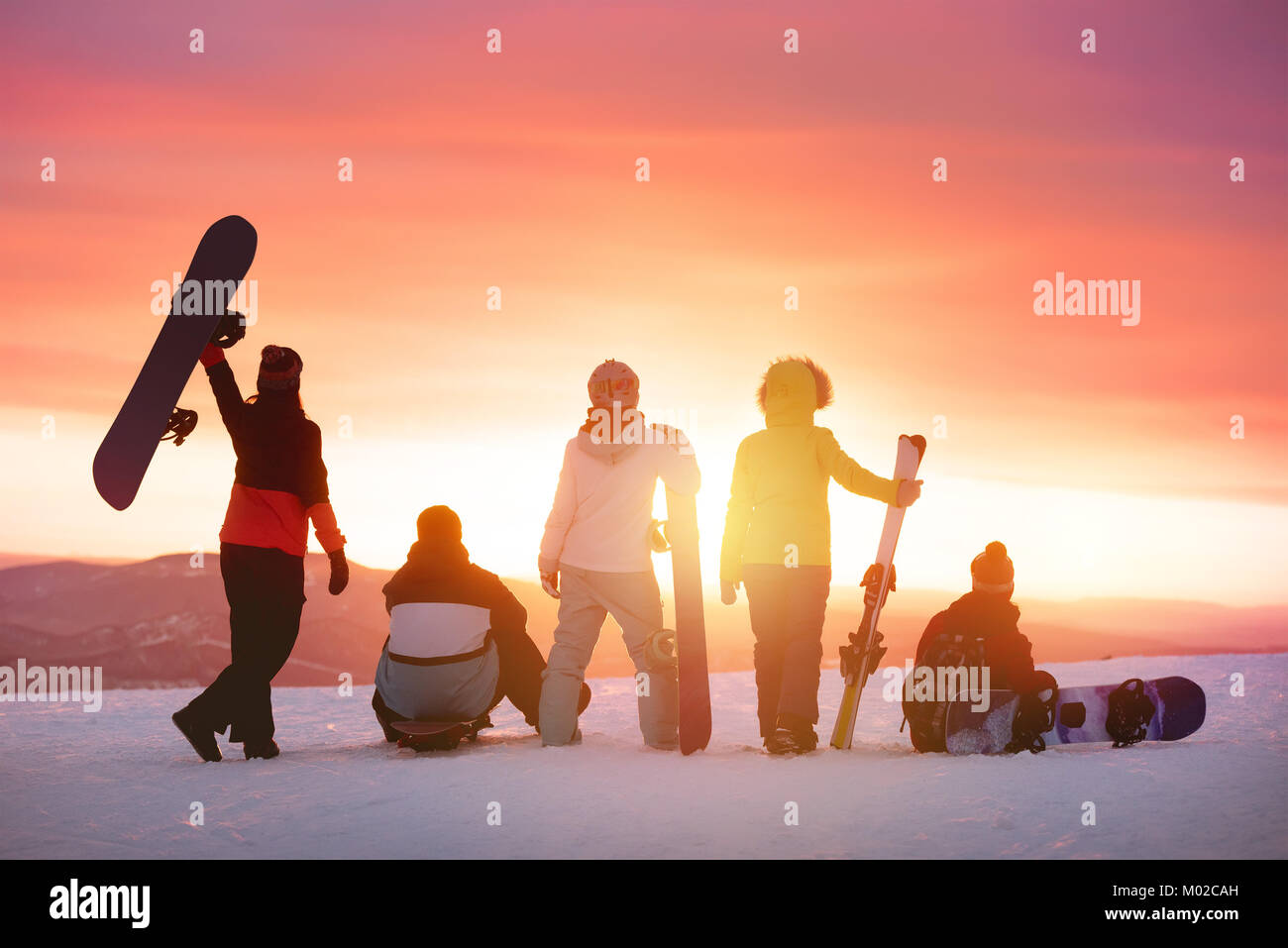Happy friends at ski resort against sunset Stock Photo