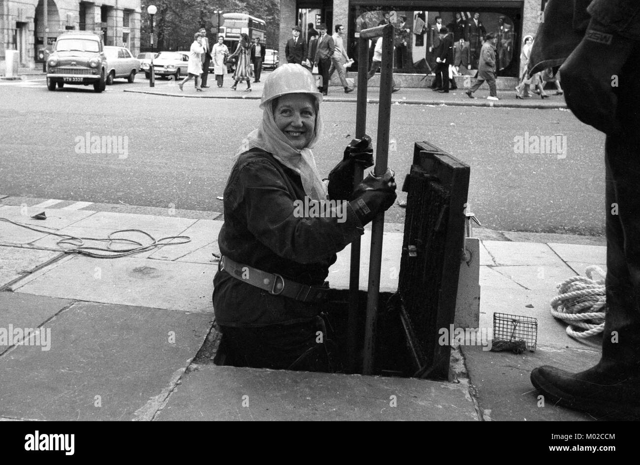 Mrs Ann Forbes-Cockell, a councillor of the Greater London Council, goes down through a Chelsea manhole to see London's sewers. Stock Photo