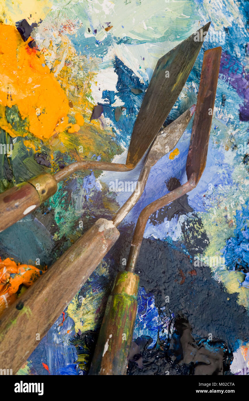 Well used artists palette knives on a multicoloured paint palette