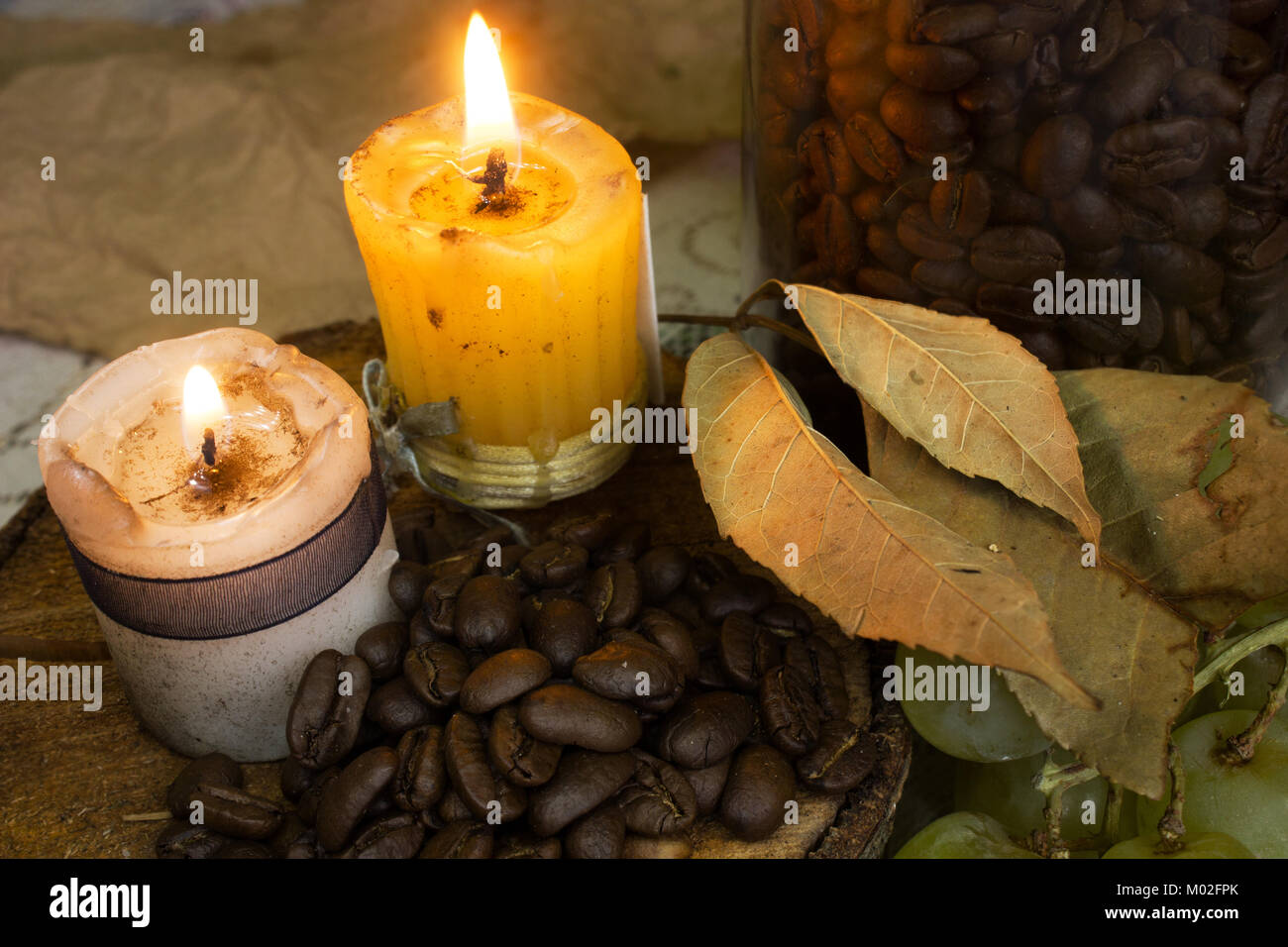 coffee beans on rustic wood, two candles and dry leaves, autumn Stock Photo