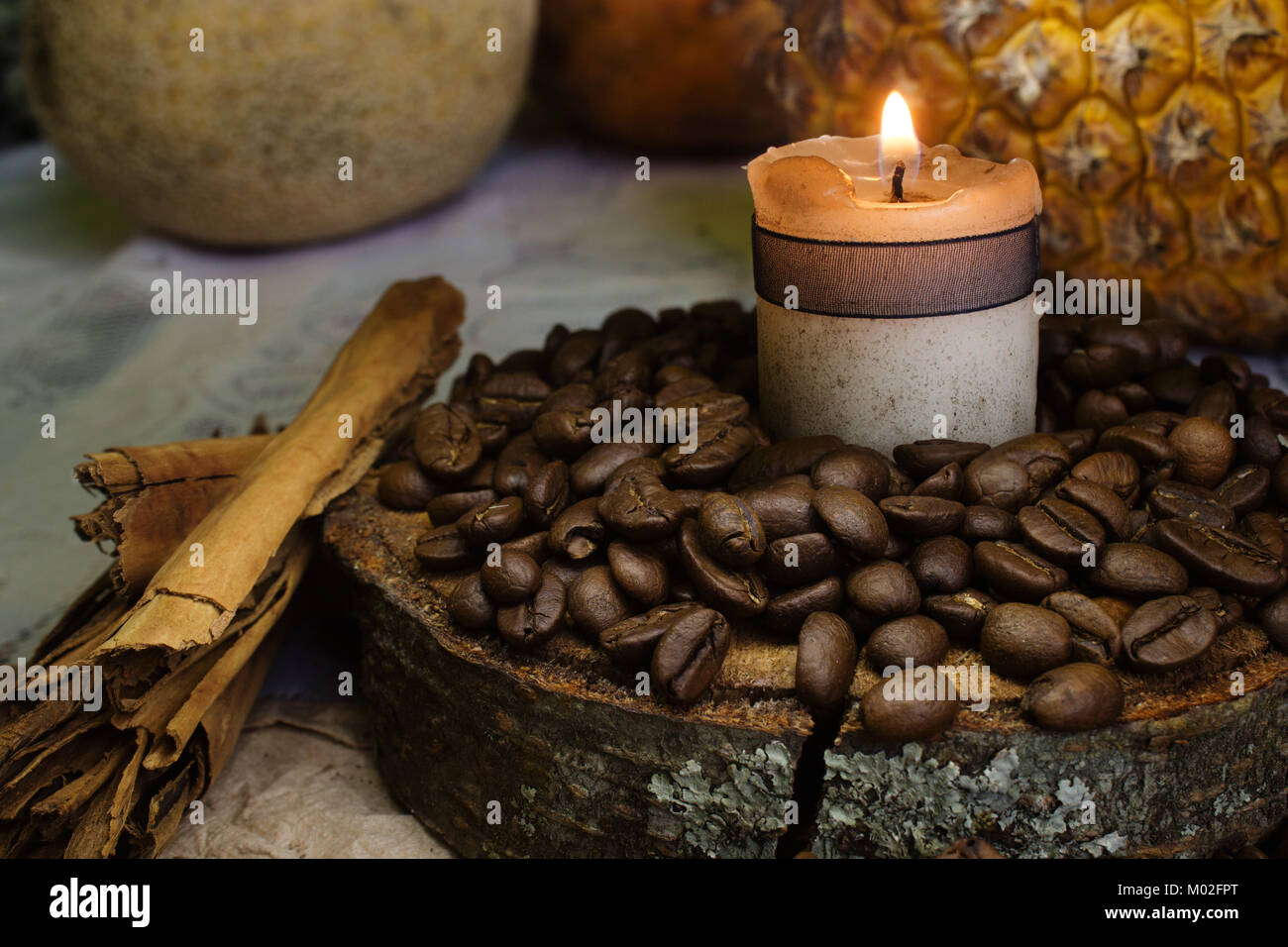 coffee beans on rustic wood, one candle and stick of cinnamon, pineapple on background Stock Photo