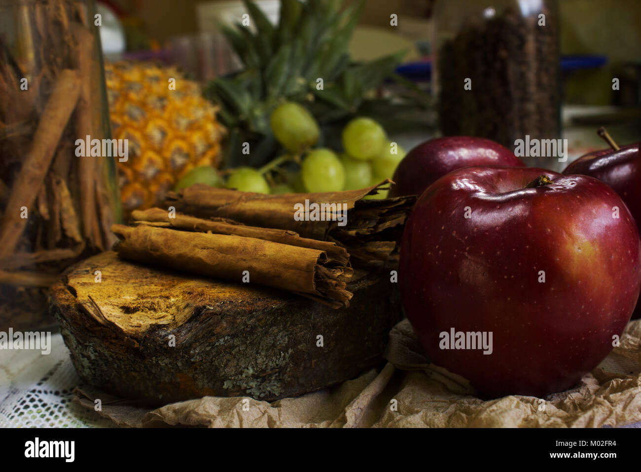 cosy scene of coffee beans on rustic wood, sticks of cinnamon, red apples, green grapes Stock Photo