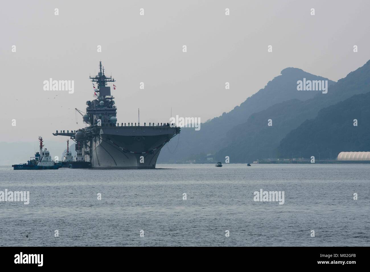 Sailors man the rails of the amphibious assault ship USS Wasp (LHD 1) as the ship arrives to Sasebo, Japan. Stock Photo