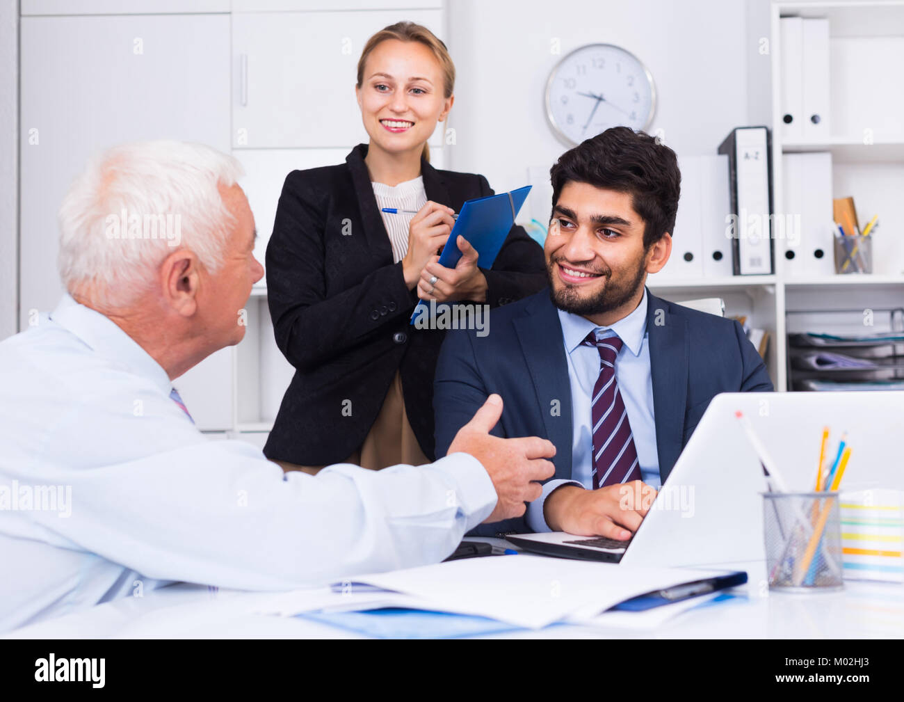 Mature man is talking to colleague, while the secretary writing ...