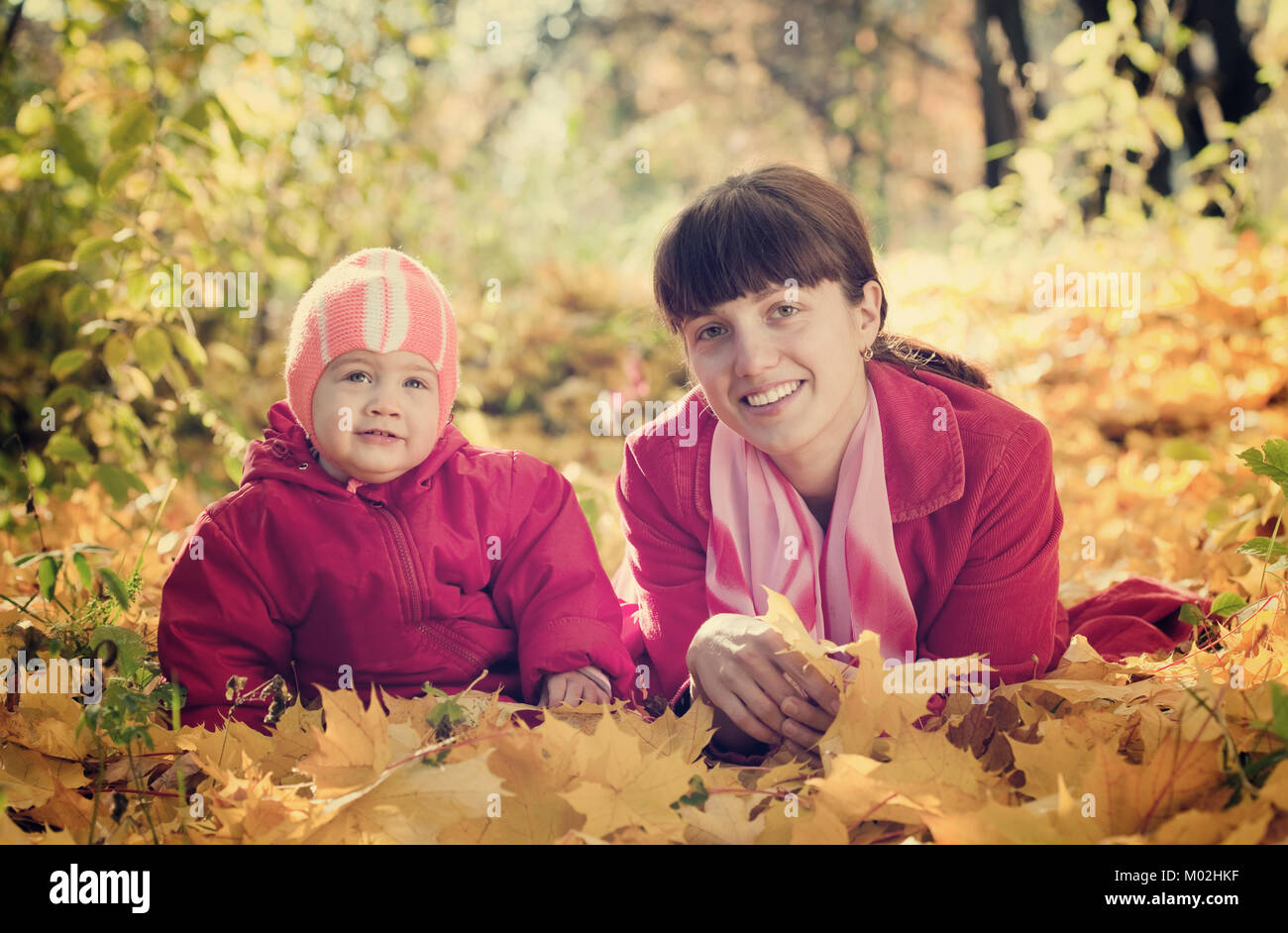 Mother and baby laying on maple leaves in autumn park Stock Photo - Alamy