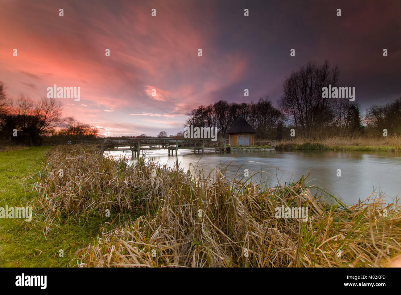 Sunset and red sky - Eel Trap and House on River Text near Longstock, Hampshire UK Stock Photo