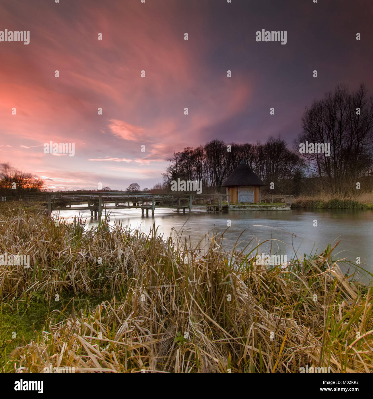Sunset and red sky - Eel Trap and House on River Text near Longstock, Hampshire UK Stock Photo