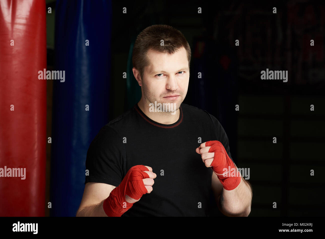 Serious boxing fighter man portrait on dark gym background Stock Photo