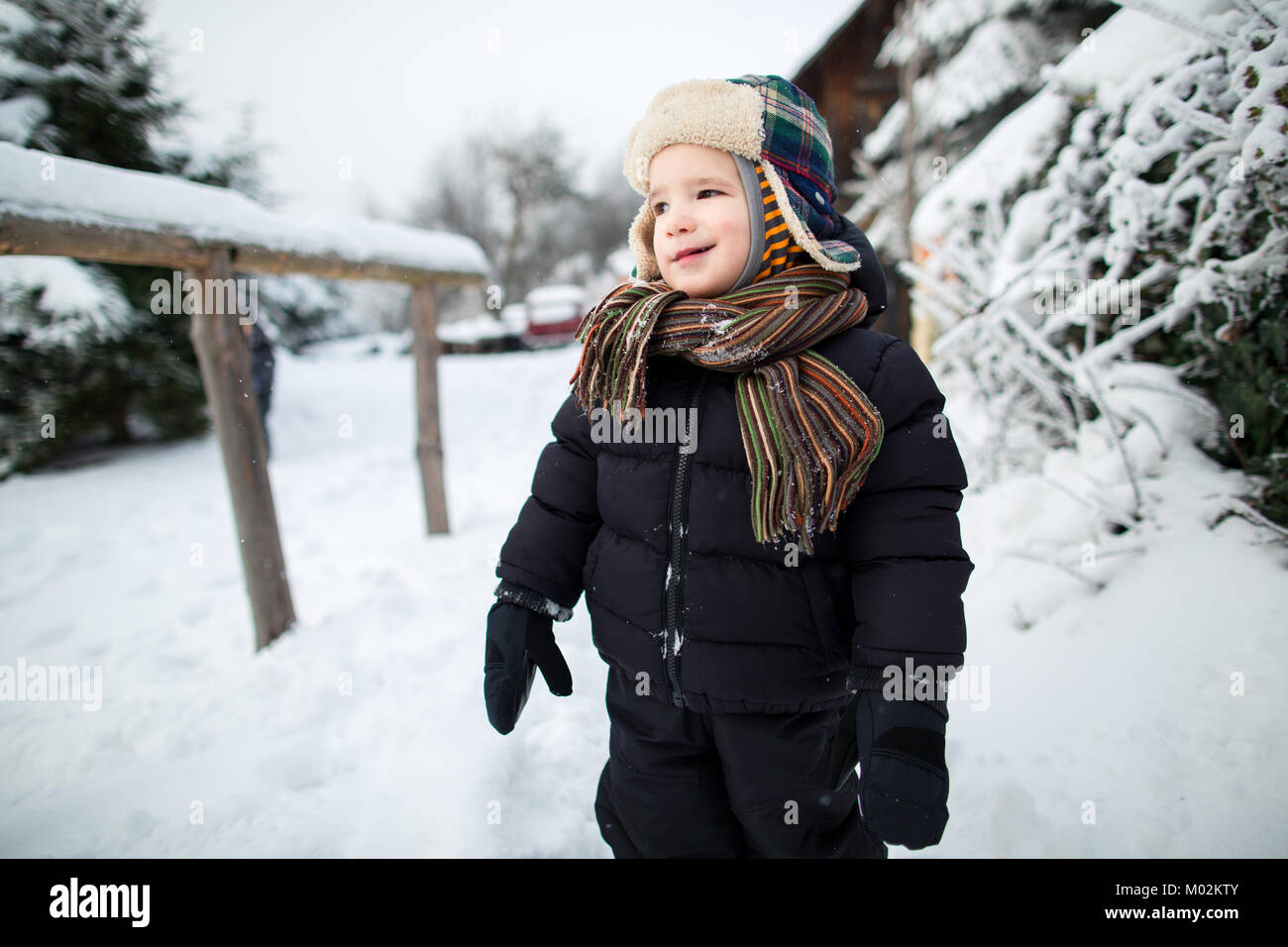 Little child with gentle smile enjoying a snowy day outside. Boy having fun in the snow. Stock Photo