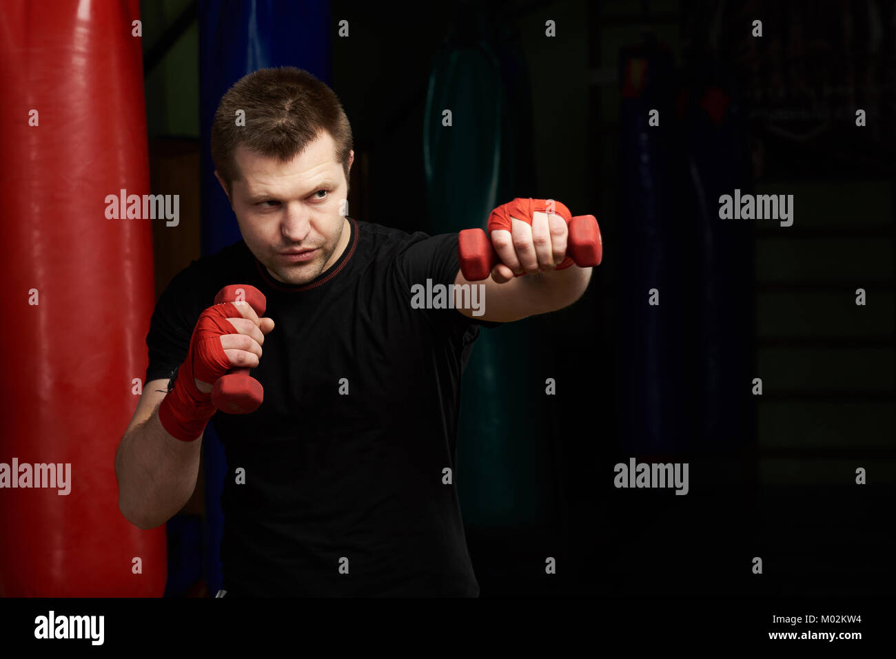 Making boxing punch stronger. Man punching with dumbbells Stock Photo