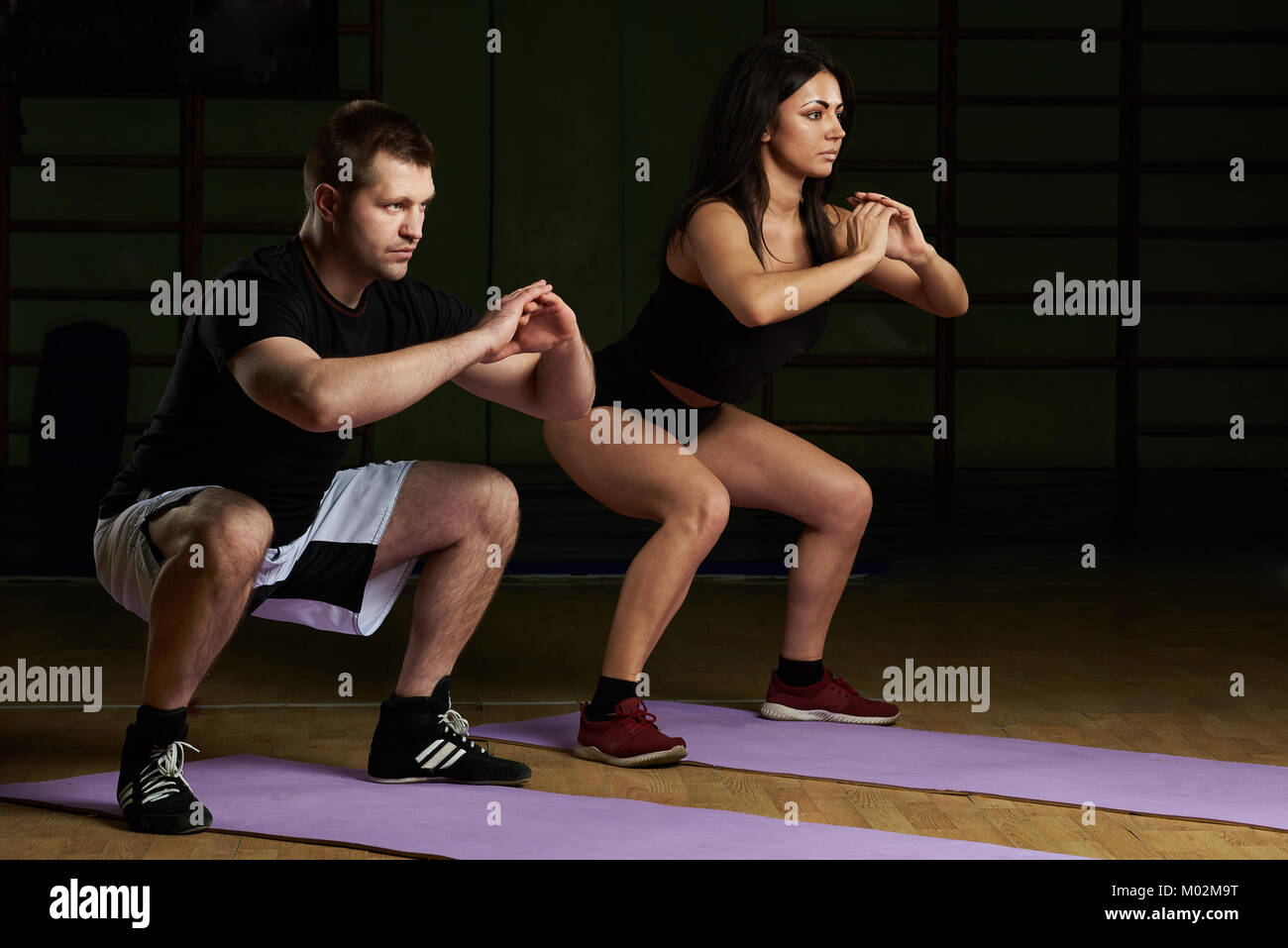 Man and woman doing squat exercise on gym background Stock Photo