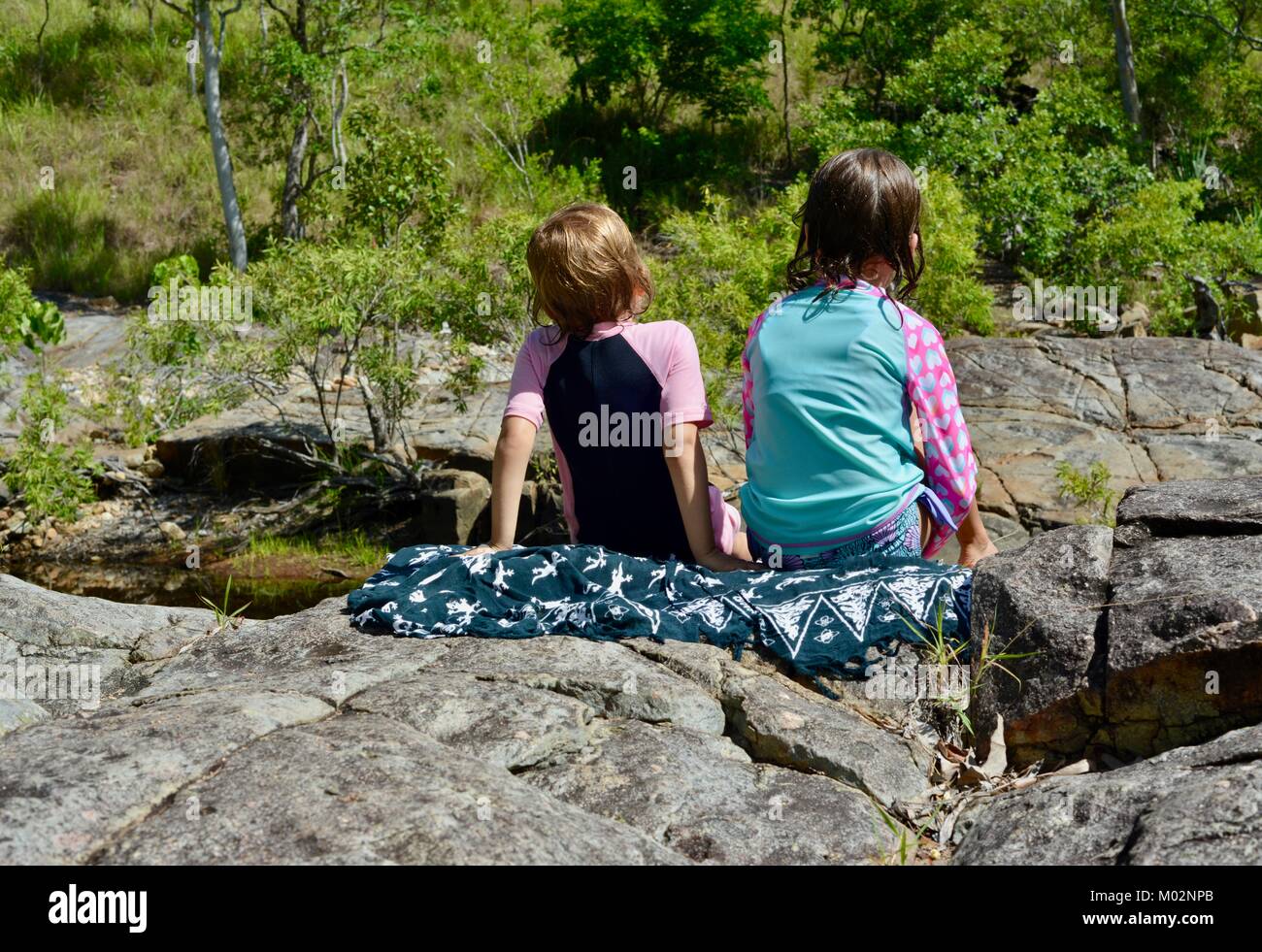 Two children sitting on rocks near a river, Alligator Creek, Bowling ...