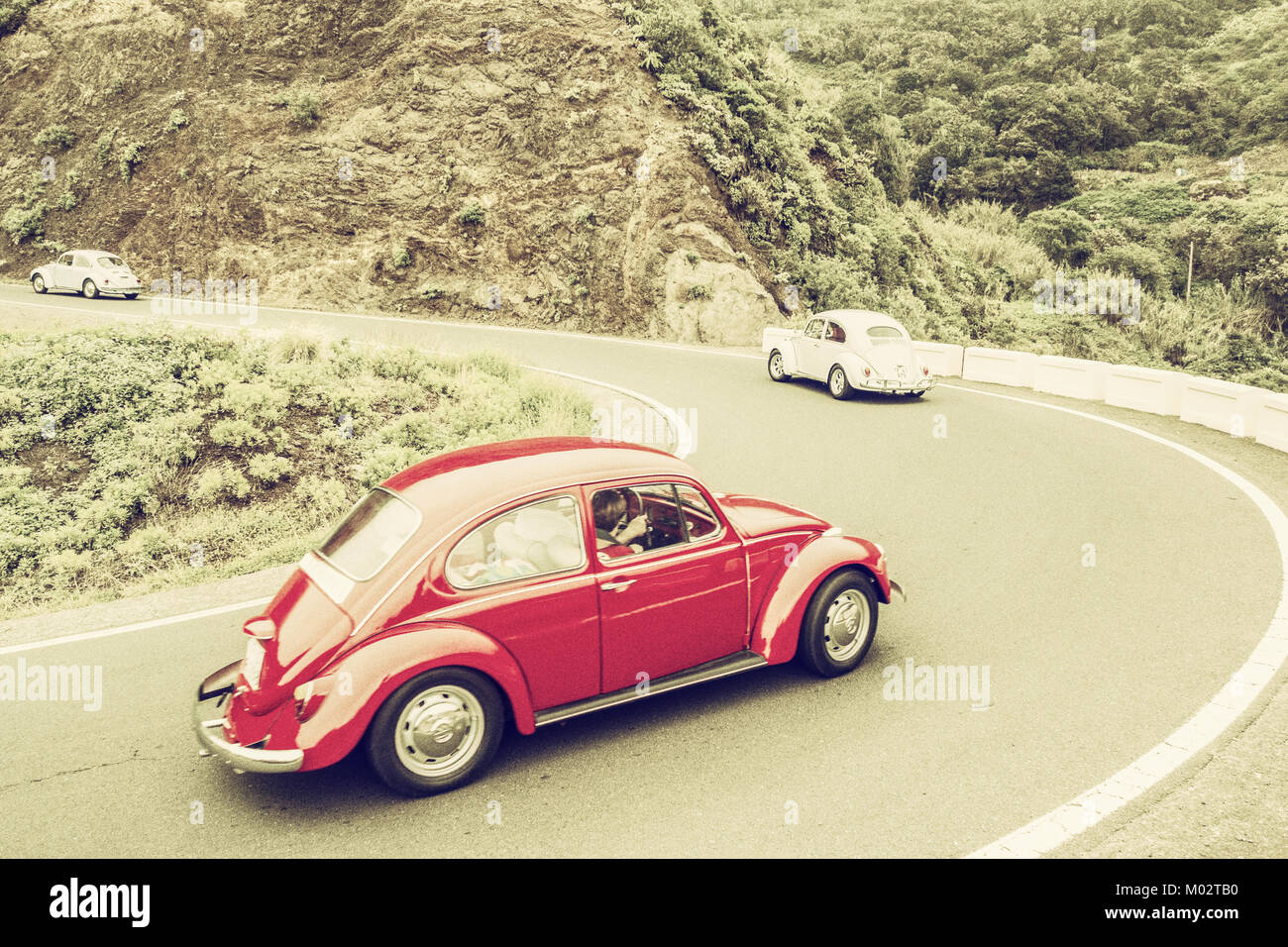 Retro, vintage processing of Volkswagen Beetle on mountain road. Stock Photo