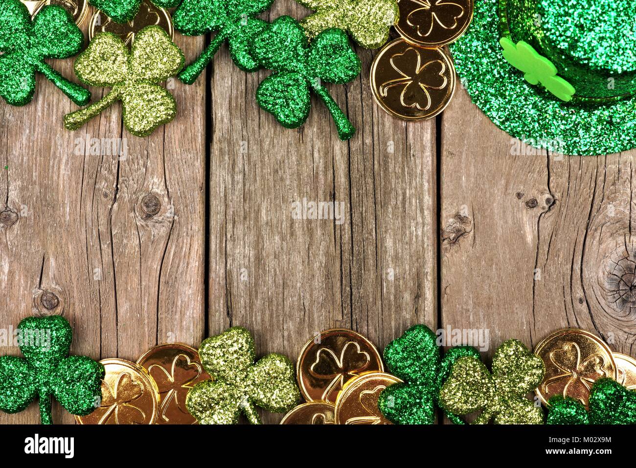 St Patricks Day double border of shamrocks, gold coins and leprechaun hat over rustic wood Stock Photo
