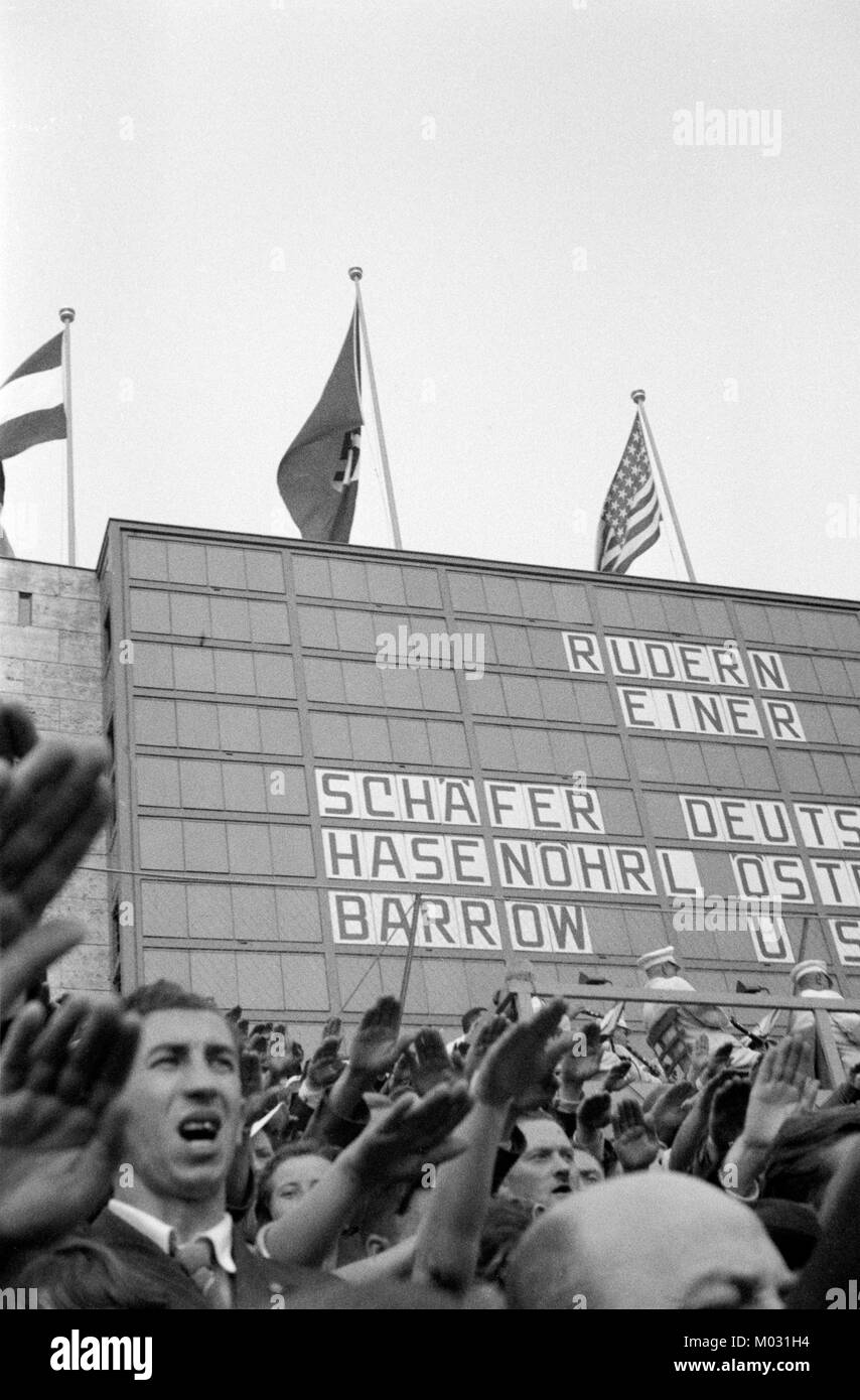 An image of spectators in front of a scoreboard at the 1936 Summer Olympic Games in Berlin, Germany. Many of the spectators can be seen giving the Nazi Salute. Stock Photo