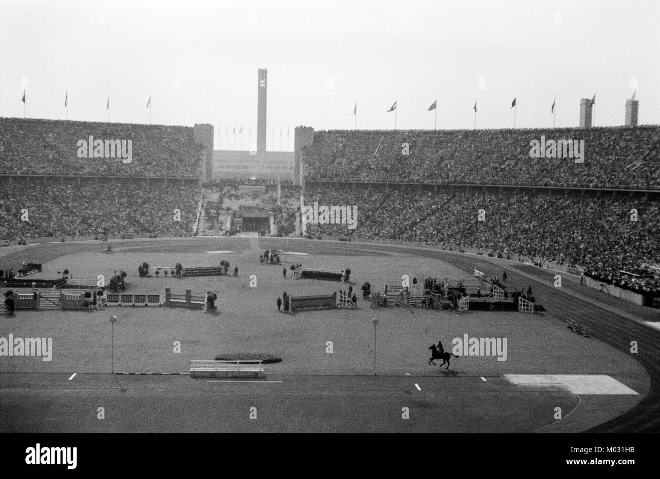 The Berlin Olympic Stadium hosting the 1936 Summer Olympics. An equestrian event underway.To outdo the Los Angeles games of 1932, Adolf Hitler had built a new 100,000-seat track and field stadium, six gymnasiums, and many other smaller arenas. The games were the first to be televised, and radio broadcasts reached 41 countries. Stock Photo