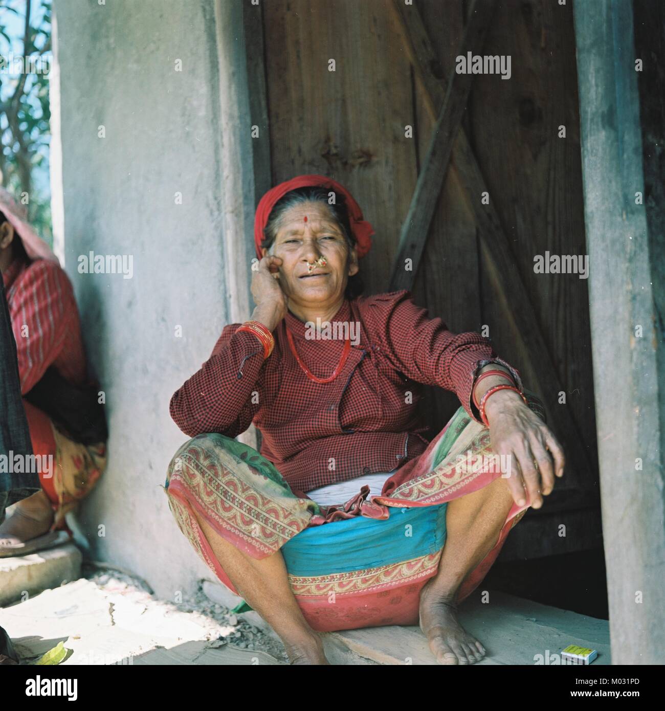 A Dalit woman in North Western Nepal sits outside her house. Stock Photo