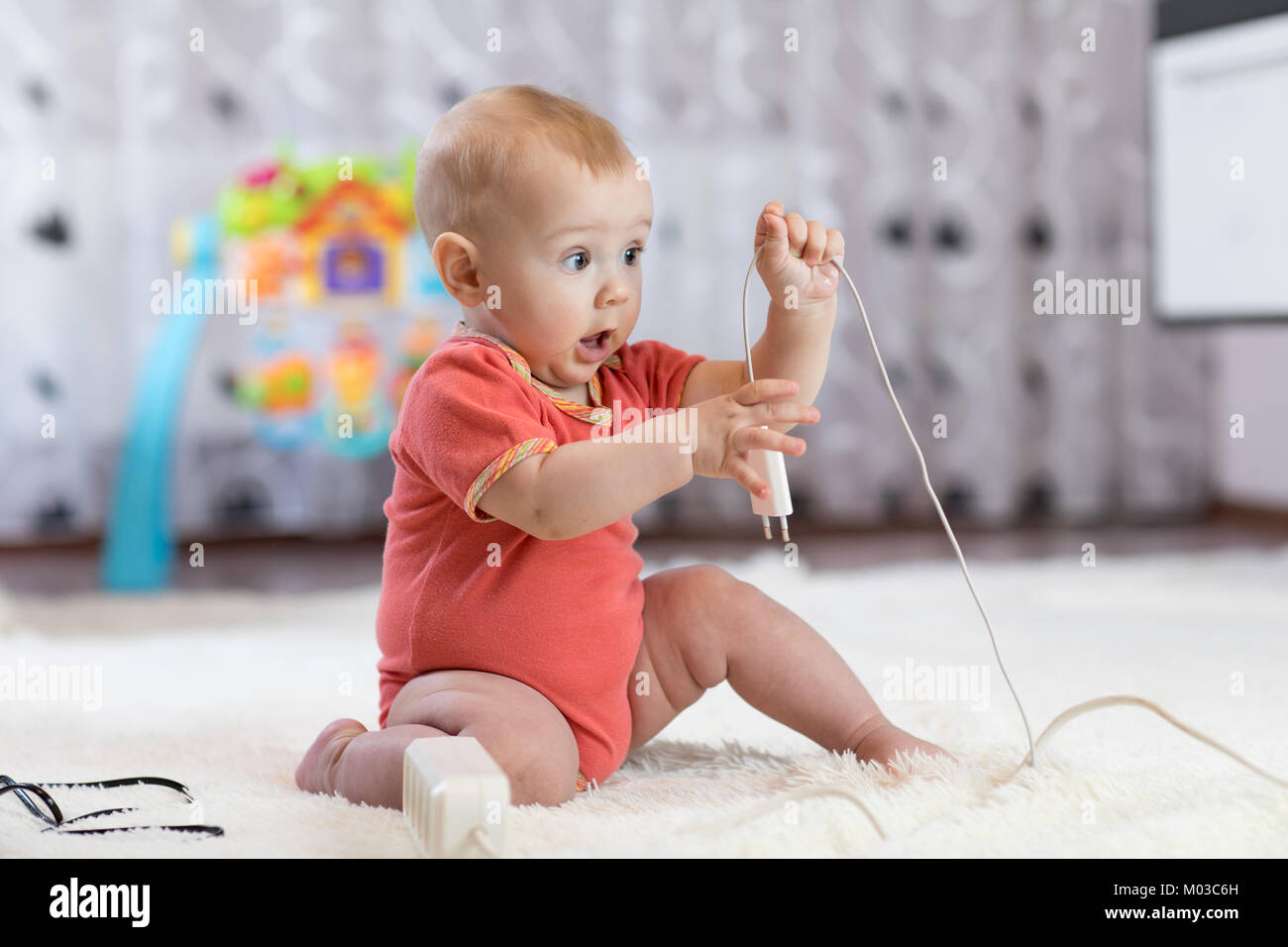 Funny baby boy pulling cables from electrical extension Stock Photo