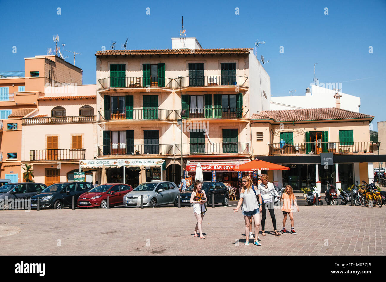 Alcudia, Mallorca, Spain - May 23, 2015: Family of tourists walking along at historical town part of Alcudia with its traditional house and cafe. Carl Stock Photo
