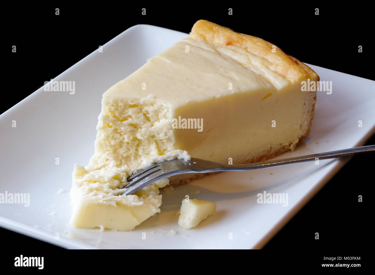 Plain baked cheesecake with cake on fork on white ceramic plate. Black background. Stock Photo