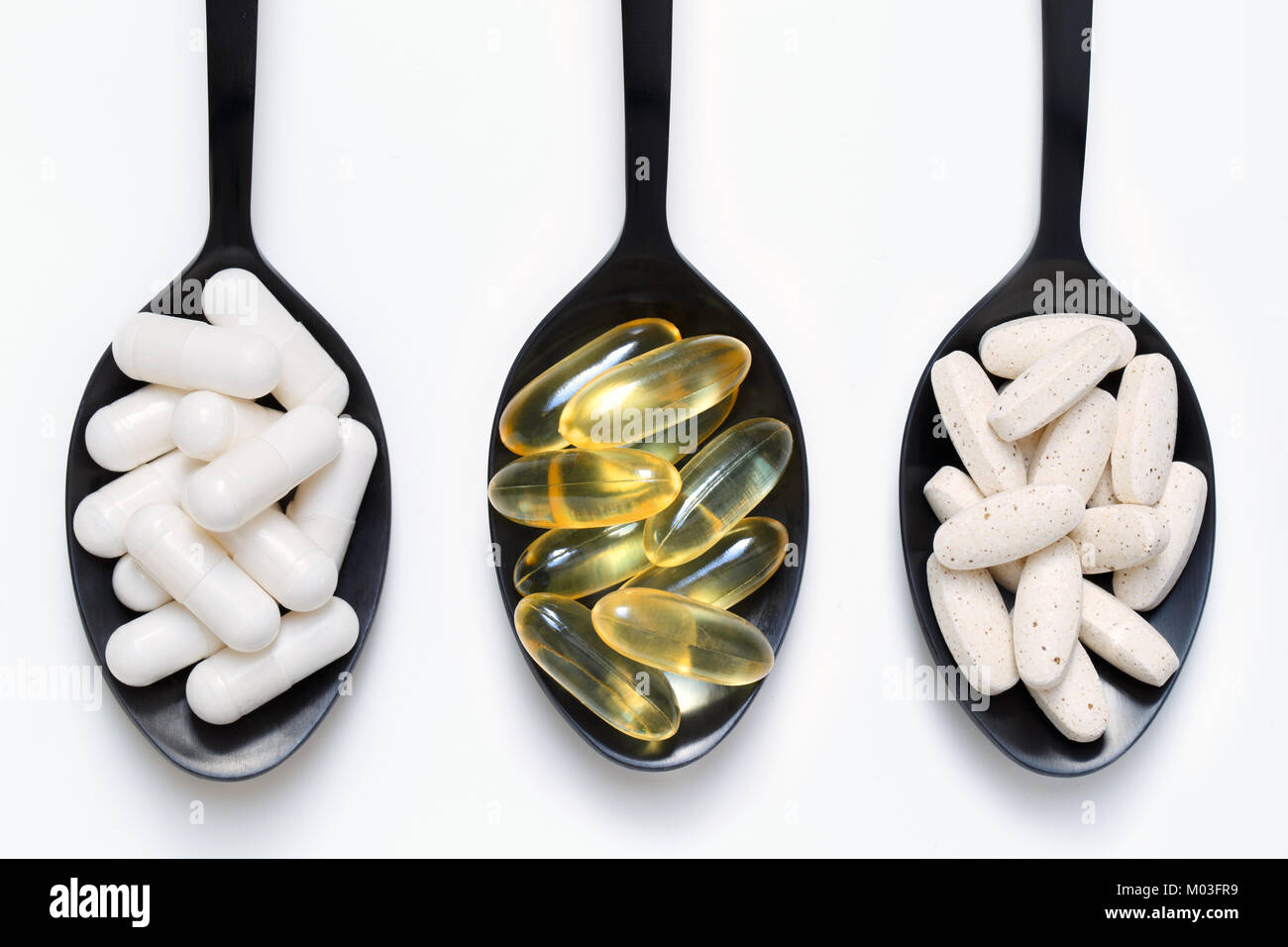 Vitamins, fish oil and minerals on black spoons against white background Stock Photo Alamy