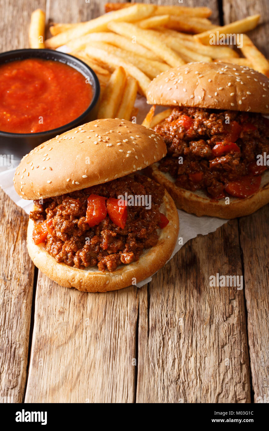 Tasty Sloppy Joe sandwiches with beef and French fries, ketchup closeup on the table. vertical Stock Photo