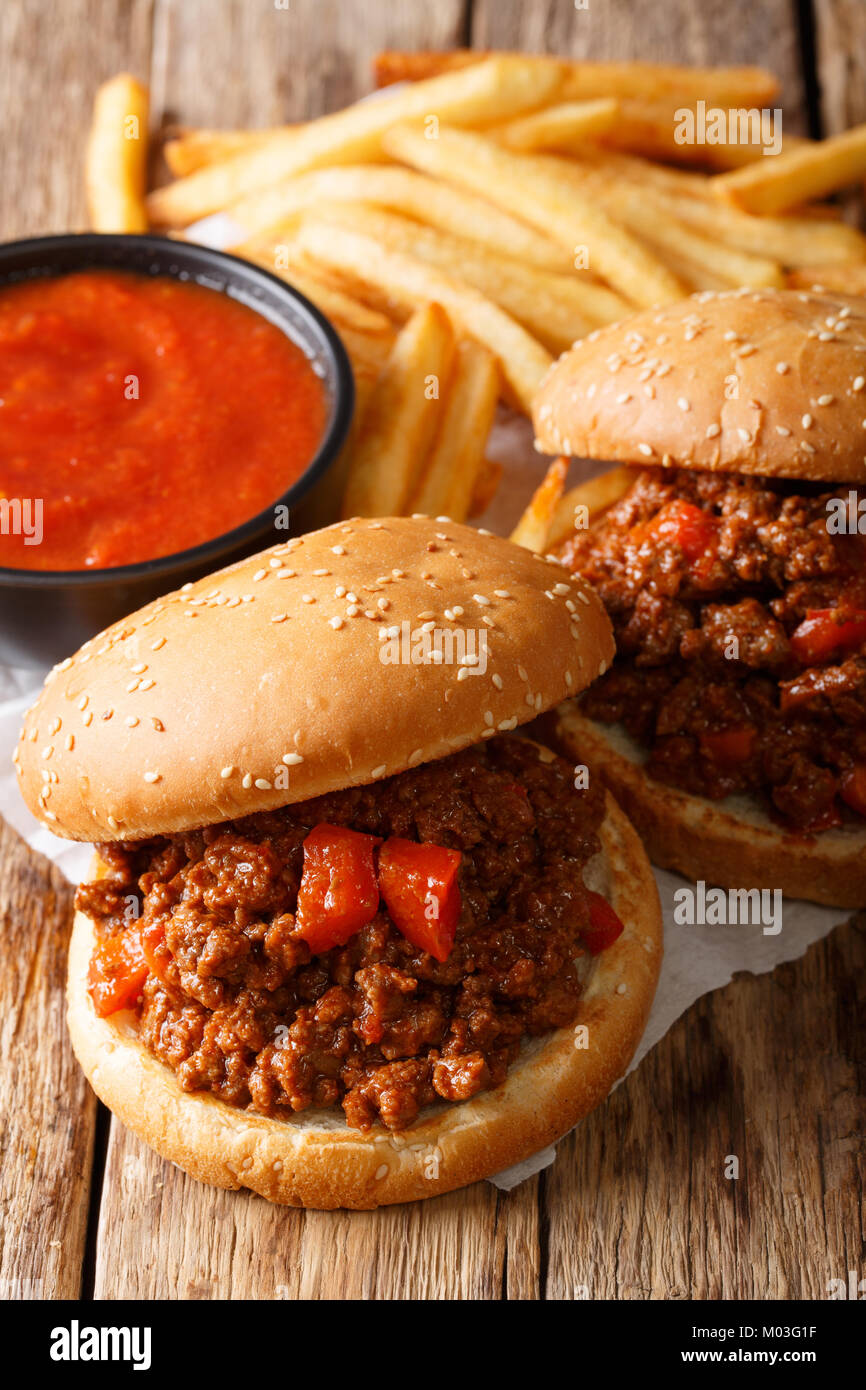 Fast food: sandwich Sloppy Joe with tomato sauce and fries close-up on the table. vertical Stock Photo