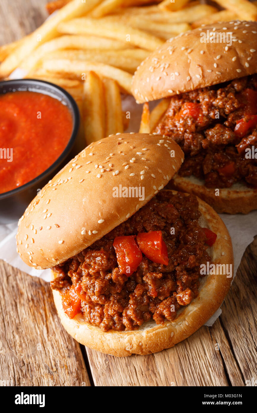 Homemade Sandwich Sloppy Joes with sauce and French fries close-up on the table. vertical Stock Photo
