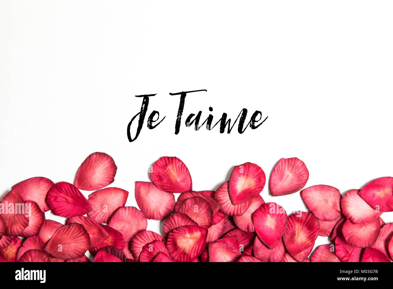 Red rose petals with je taime message Stock Photo