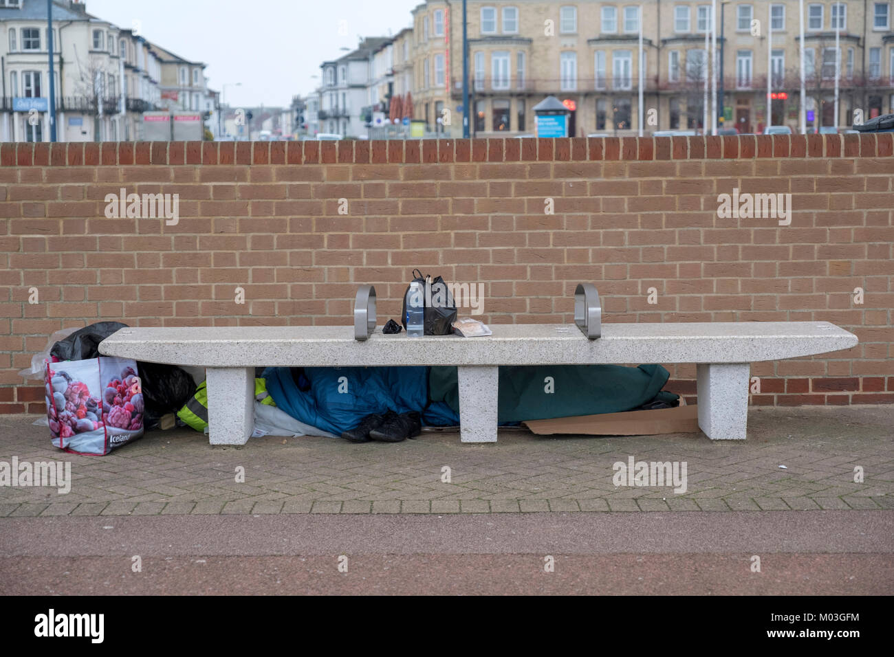 Hidden homeless person with gifts of food and water, sleeps on the pleasure beach promenade, Great Yarmouth UK Stock Photo