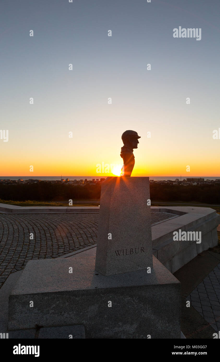 NC01338-00...NORTH CAROLINA - Sunrise over the Atlantic Ocean behind the bust of Wilbur Wright at the base of the monument at the Wright Brothers Nati Stock Photo