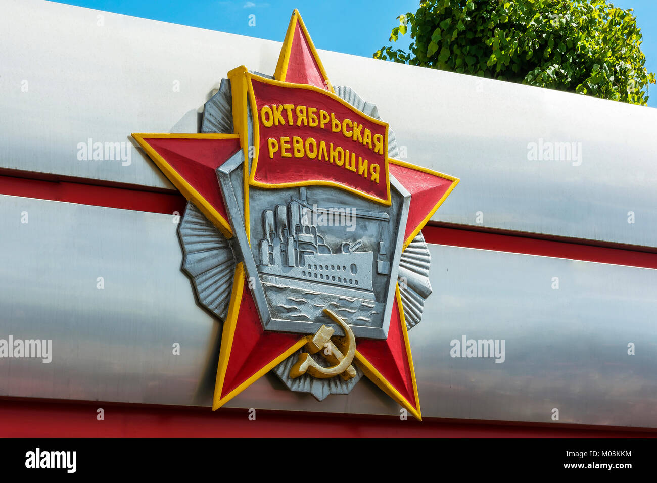 The bas-relief of the order of the October revolution closeup on blue sky background and tree with the words 'October revolution' Stock Photo