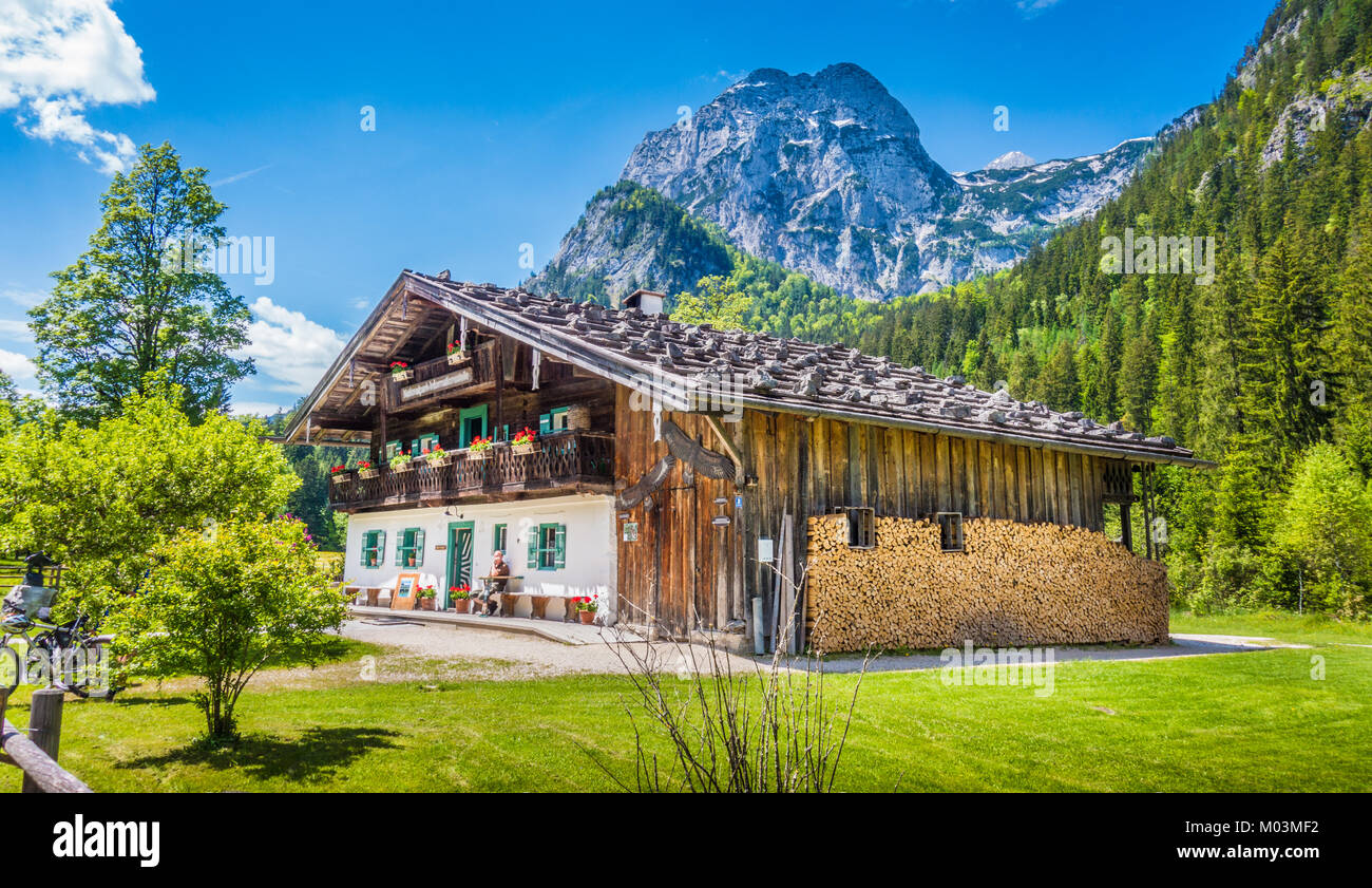 Panoramic view of idyllic mountain scenery in the Alps with traditional farmhouse and fresh green mountain pastures in summer Stock Photo