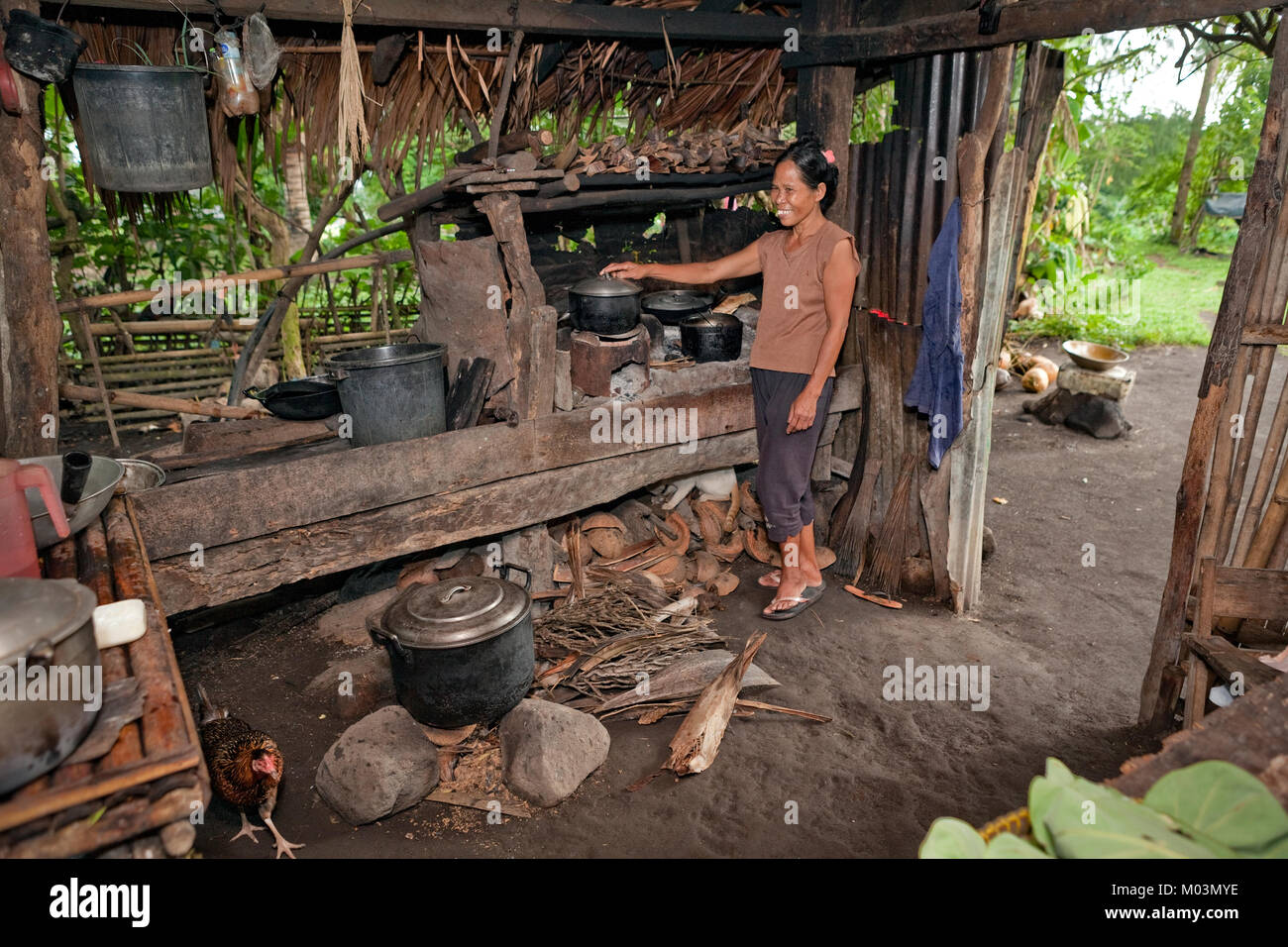 A Filipino woman cooks a meal over open flame in her outdoor 'dirty