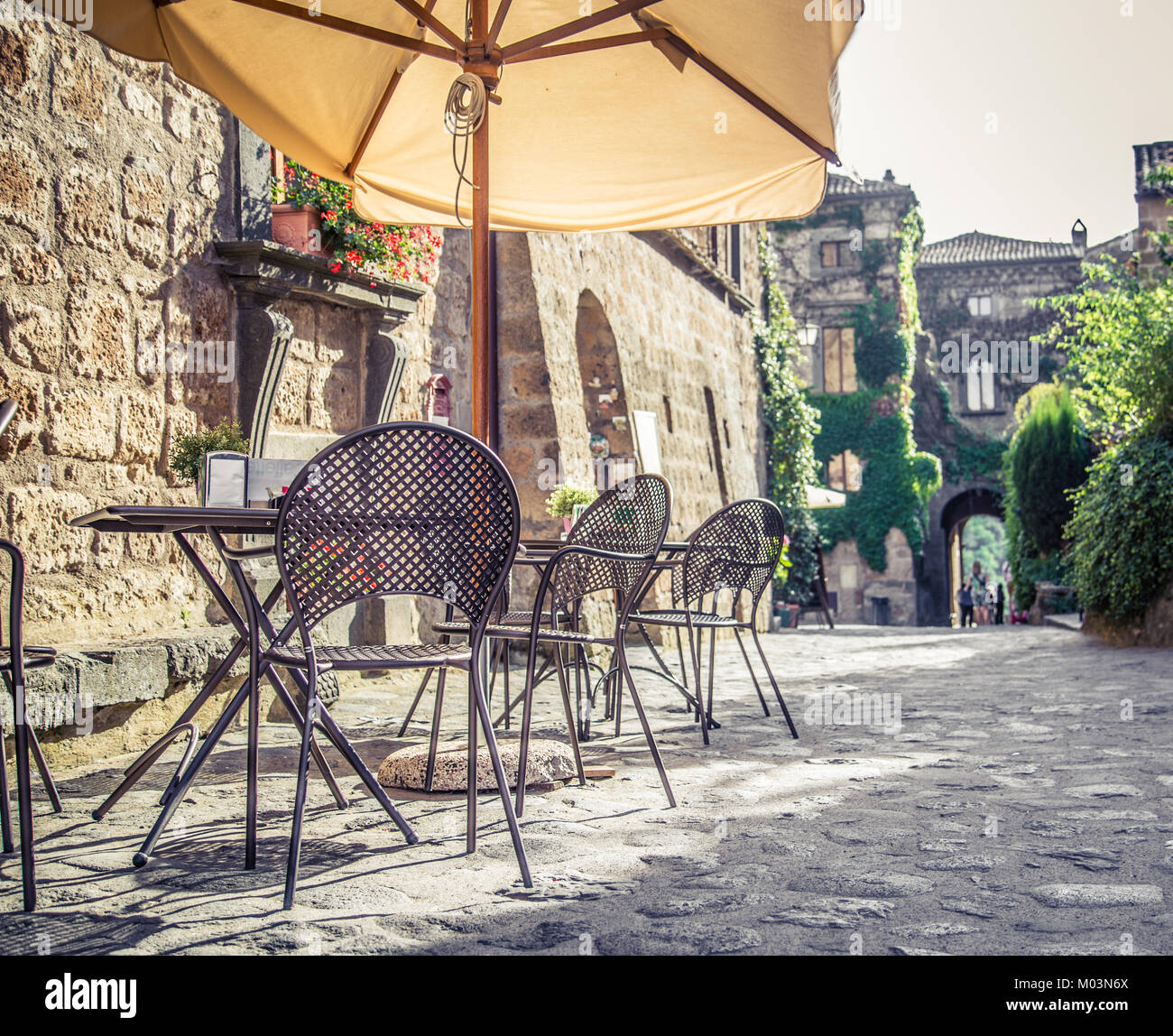 Cafe with tables and chairs in an old street in Europe with retro vintage Instagram style filter effect Stock Photo