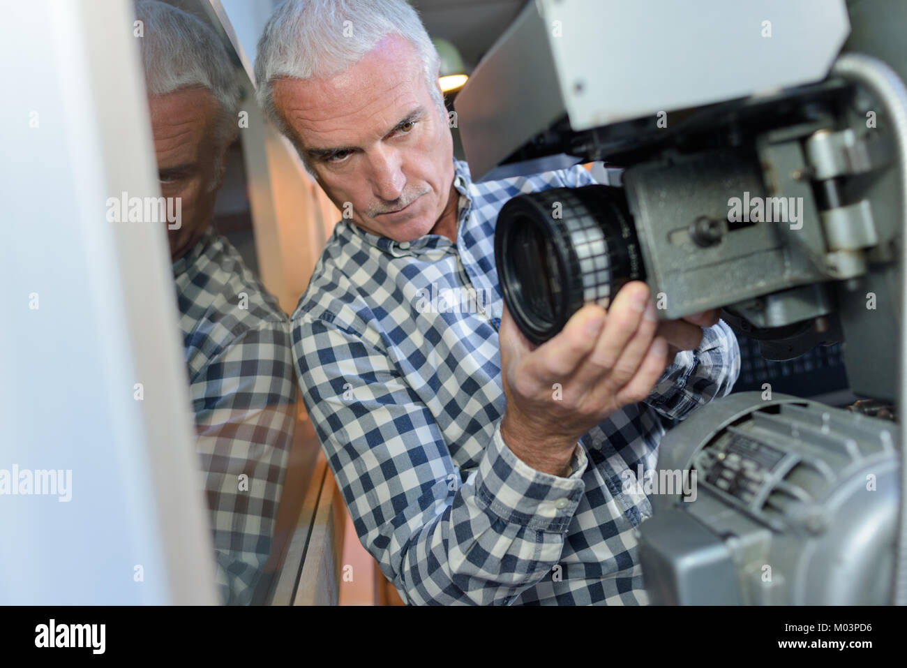 senior worker adjusting machine at industrial factory site Stock Photo ...