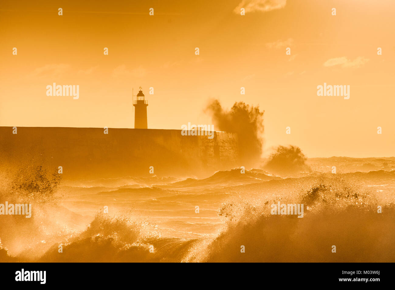 Newhaven, East Sussex. 18th Jan, 2018. UK Weather.A bright start to the day on the South Coast. Overnight gales subsiding leaving a brisk Westerly wind whipping up the surf backlit by the Orange glow of the rising Sun. . Stock Photo